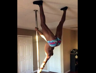 Dark-hued male stripper flipping on a pole.